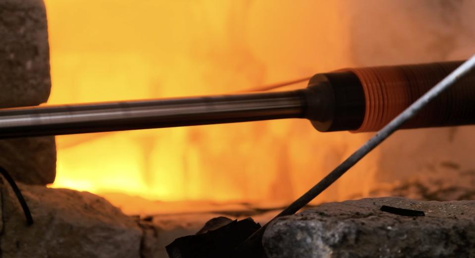 a machine rolls molten glass into coils