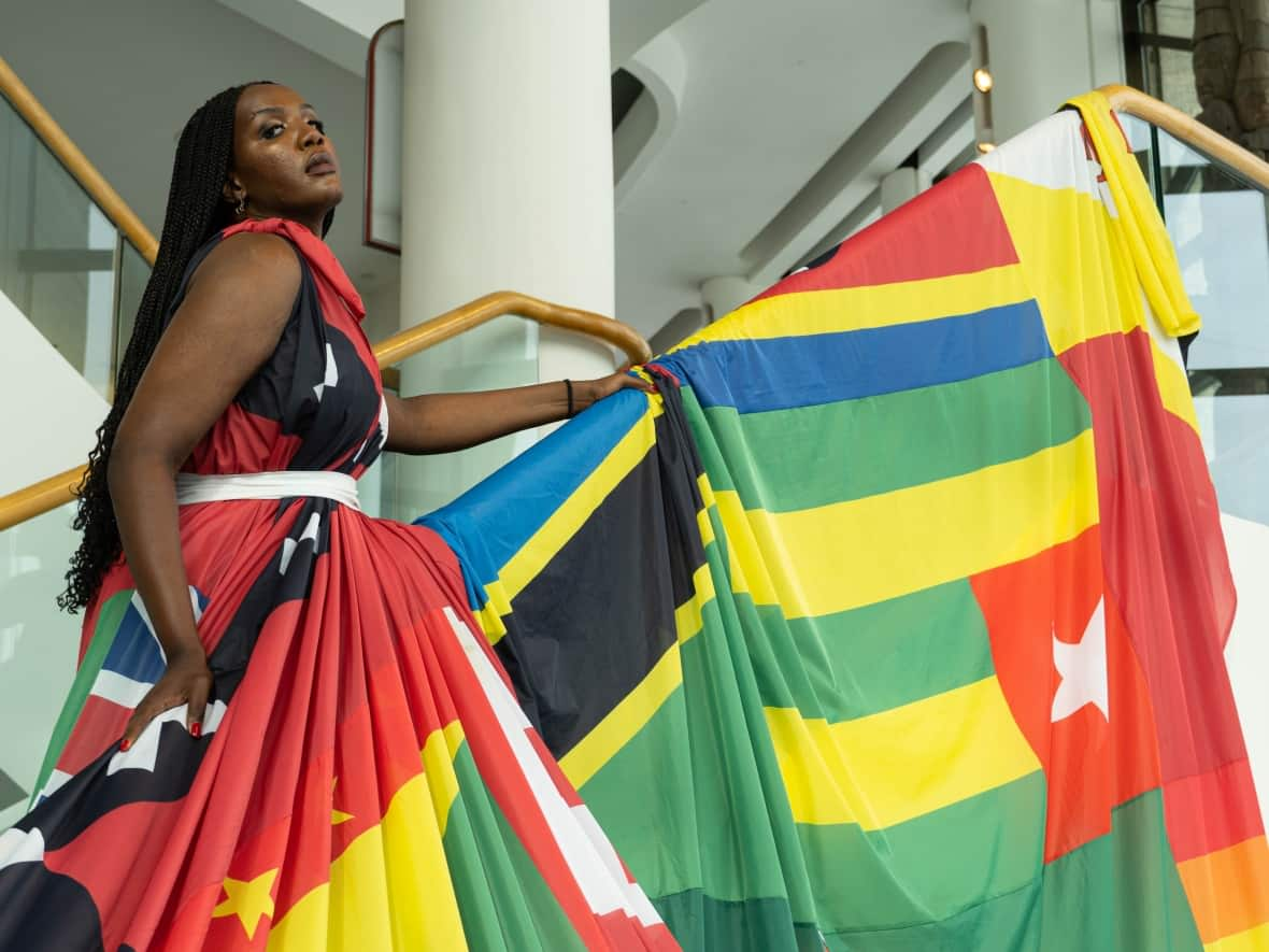 Transgender rights advocate Alicia Kazobinka models the Amsterdam Rainbow Dress at the Canadian Museum of History in Gatineau, Que., on Dec. 7, 2021. Now living in Montreal, Kazobinka is originally from Burundi, one of the countries whose flag is included on the dress. (Jean Delisle/CBC - image credit)