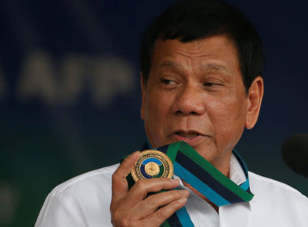 Philippine Pesident Rodrigo Duterte holds an emblem of the Armed forces as he speaks at the change of command for the new Armed Forces chief at a military camp in Quezon city, Metro Manila, December 7, 2016. REUTERS/Erik De Castro