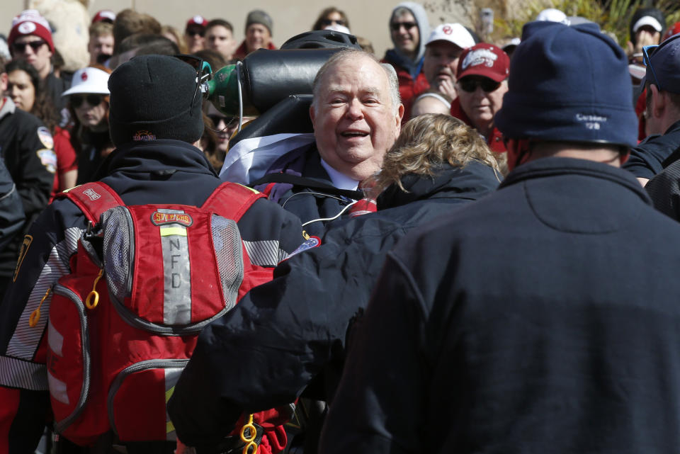 David Boren, president of the University of Oklahoma, is taken away by medical personnel and security during the unveiling of a statue of former head football coach Bob Stoops in Norman, Okla., Saturday, April 14, 2018. (AP Photo/Sue Ogrocki)