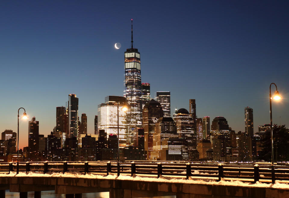 The moon rises in the pre-dawn sky above lower Manhattan and One World Trade Center in New York City. Photo: Gary Hershorn/Getty Images