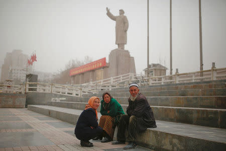 Ethnic Uighurs sit near a statue of China's late Chairman Mao Zedong in Kashgar, Xinjiang Uighur Autonomous Region, China, March 23, 2017. REUTERS/Thomas Peter