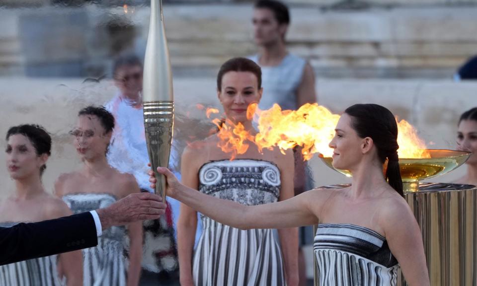<span>Actor Mary Mina, playing an ancient Greek high priestess, holds the Olympic torch at a ceremony in Athens before it began its sea journey to France.</span><span>Photograph: Petros Giannakouris/AP</span>