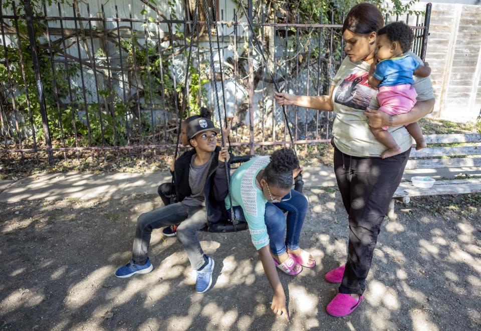 Ashley Joiner, 30, carries Gemirah Jerome as she pushes Quania Taplin, Geyarian Jerome and Marielle Jerome on a swing near their apartment. The family has seven children 10 and younger.