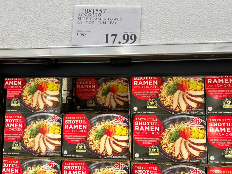 boxes of ramen piled together in a display at Costco with 17.99 price sign above them on wall