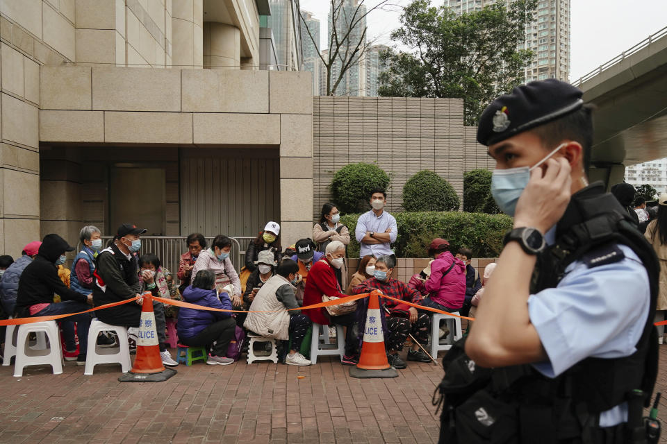 A policeman stands watch as people wait outside the West Kowloon Magistrates' Courts ahead of the national security trial for the pro-democracy activists in Hong Kong, Monday, Feb. 6, 2023. Some of Hong Kong's best-known pro-democracy activists went on trial Monday in the biggest prosecution yet under a law imposed by China's ruling Communist Party to crush dissent. (AP Photo/Anthony Kwan)