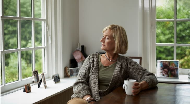 A woman ponders a significant financial decision over a cup of coffee.