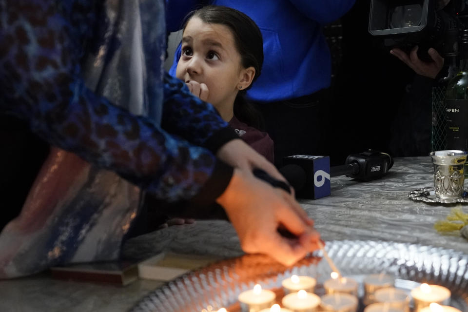 Chana Hecht, watches her mother Yehudis, wife of Rabbi Meir Hecht light candles to mark the beginning of Shabbat at the Chabad of Evanston, Ill., on Friday, Oct. 20, 2023. Judith Raanan, a member of Chabad, and her daughter Natalie were released Friday from their captivity in Gaza. (AP Photo/Charles Rex Arbogast)