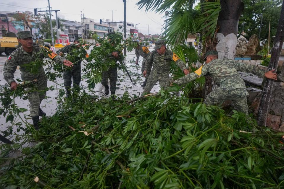 Soldiers collect branches felled by Hurricane Beryl, in Tulum, Mexico (AP)