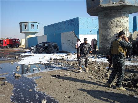 Iraqi security forces stand at the site where a suicide bomber drove a truck packed with explosives into a police checkpoint in the town of al-Alam near Tikrit, November 13, 2013. REUTERS/Stringer