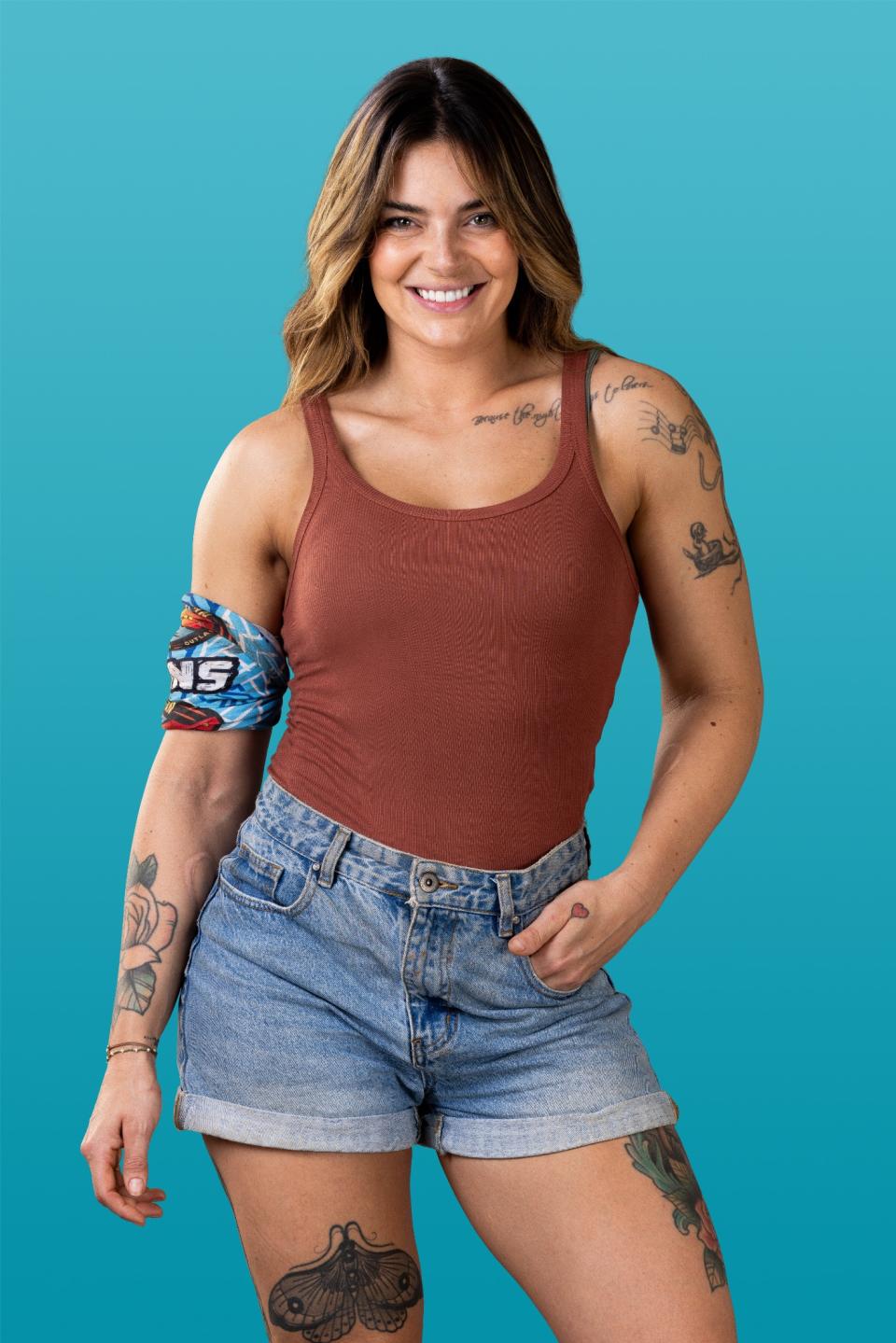 Frankie smiles at the camera in brown singlet and denim shorts.