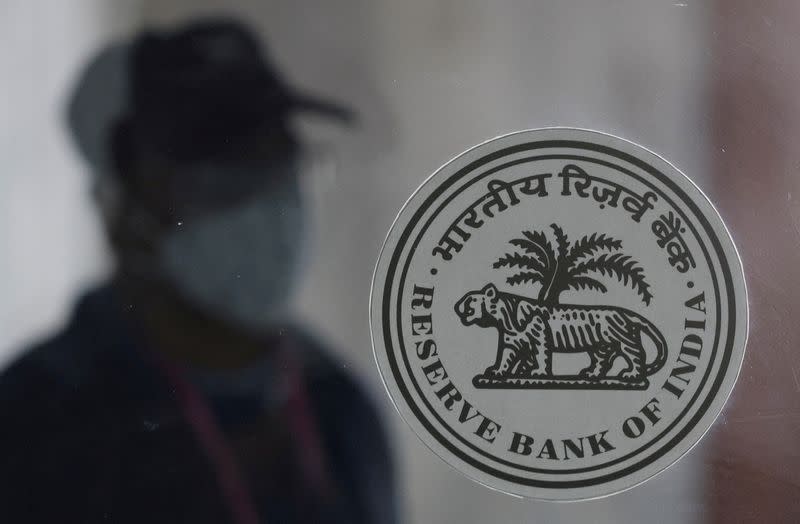 FILE PHOTO: A man walks behind the Reserve Bank of India (RBI) logo inside its headquarters in Mumbai