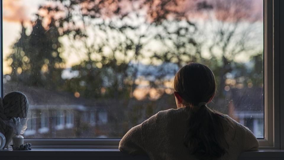 Imagen mujer mirando por la ventana.