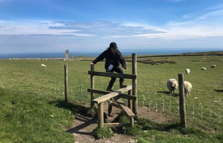 Reuters journalist Mari Saito climbs over a stile during the Cloud Appreciation Society gathering on Lundy Island