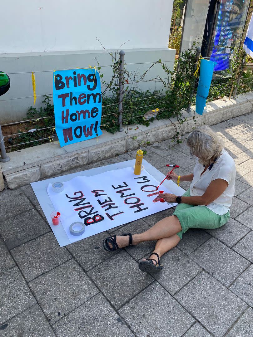 Una señora pinta un cartel en el que pide que se traigan devuelta a casa a los rehenes que secuestró el grupo terrorista Hamas