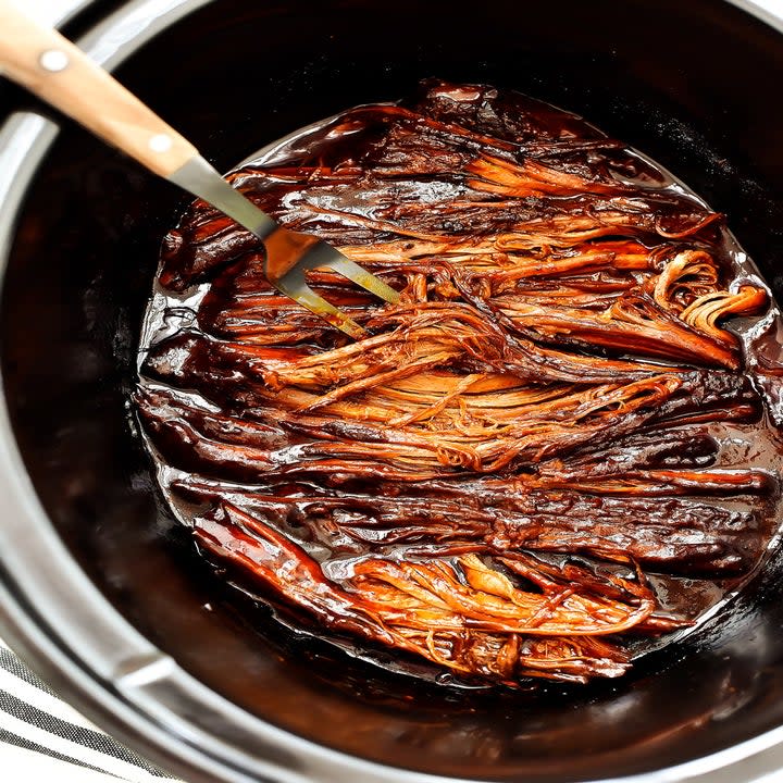 A slow cooker filled with shredded brisket.