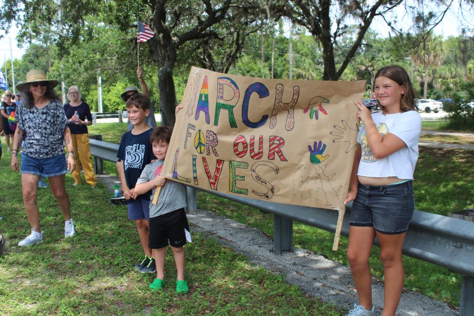 Addison Asay, 12, of Palm Coast, and her cousin, Lincoln Stallard, 7, of Washington, D.C., hold up a sign Saturday during the March for Our Lives rally in Flagler Beach.