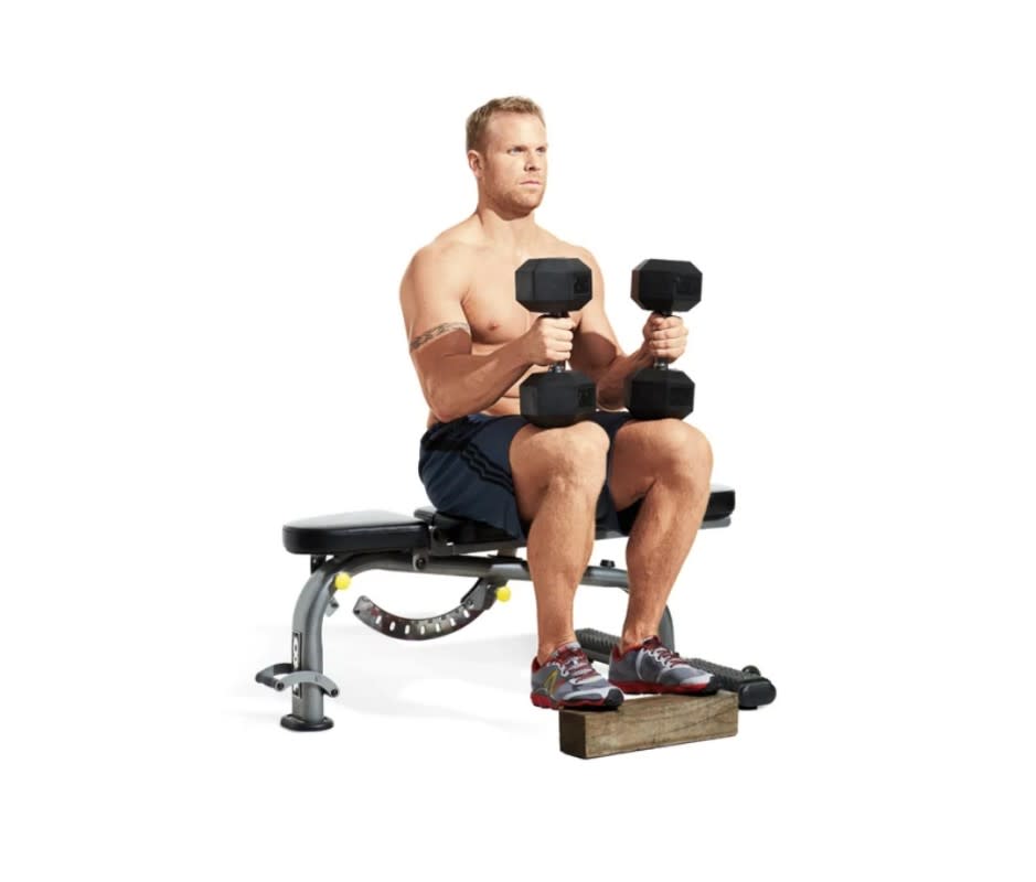<p>Beth Bischoff</p>How to Do It:<ol><li>Use a seated calf raise machine or sit on a bench and rest the balls of your feet on a block or step (and hold <a href="https://www.yahoo.com/lifestyle/11-best-adjustable-dumbbells-home-010025583.html" data-ylk="slk:dumbbells;elm:context_link;itc:0;sec:content-canvas;outcm:mb_qualified_link;_E:mb_qualified_link;ct:story;" class="link  yahoo-link">dumbbells</a> on your thighs for resistance).</li><li>Your knees should be bent 90 degrees and your toes point straight ahead.</li><li>Allow your heels to drift toward the floor until you feel a stretch in your calves.</li><li>Now drive the balls of your feet into the platform and raise your heels as high as possible. </li></ol>