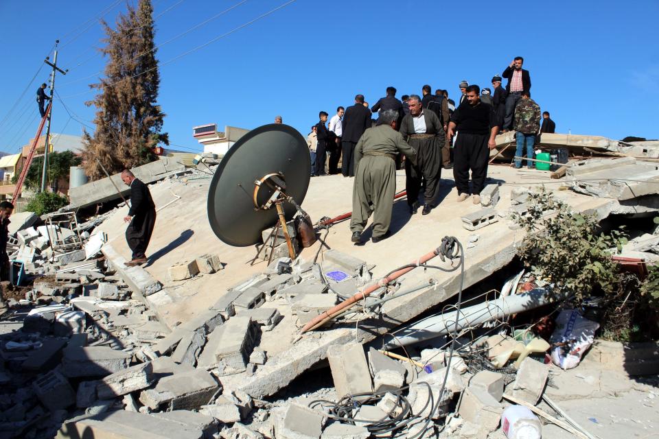 <p>Iraqi Kurdish people stand over the wreckage of a building destroyed in earthquake at Darbandikhan town, near Sulaymaniya city, northern Iraq, Nov. 13, 2017. (Photo: Abedin Taherkenareh/EPA-EFE/REX/Shutterstock) </p>