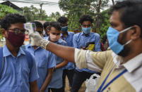 School children wearing masks get their hands sanitized and temperatures checked as they arrive to appear for state board examination during the coronavirus pandemic in Kochi, Kerala state, India, Tuesday, May 26, 2020. (AP Photo/R S Iyer)