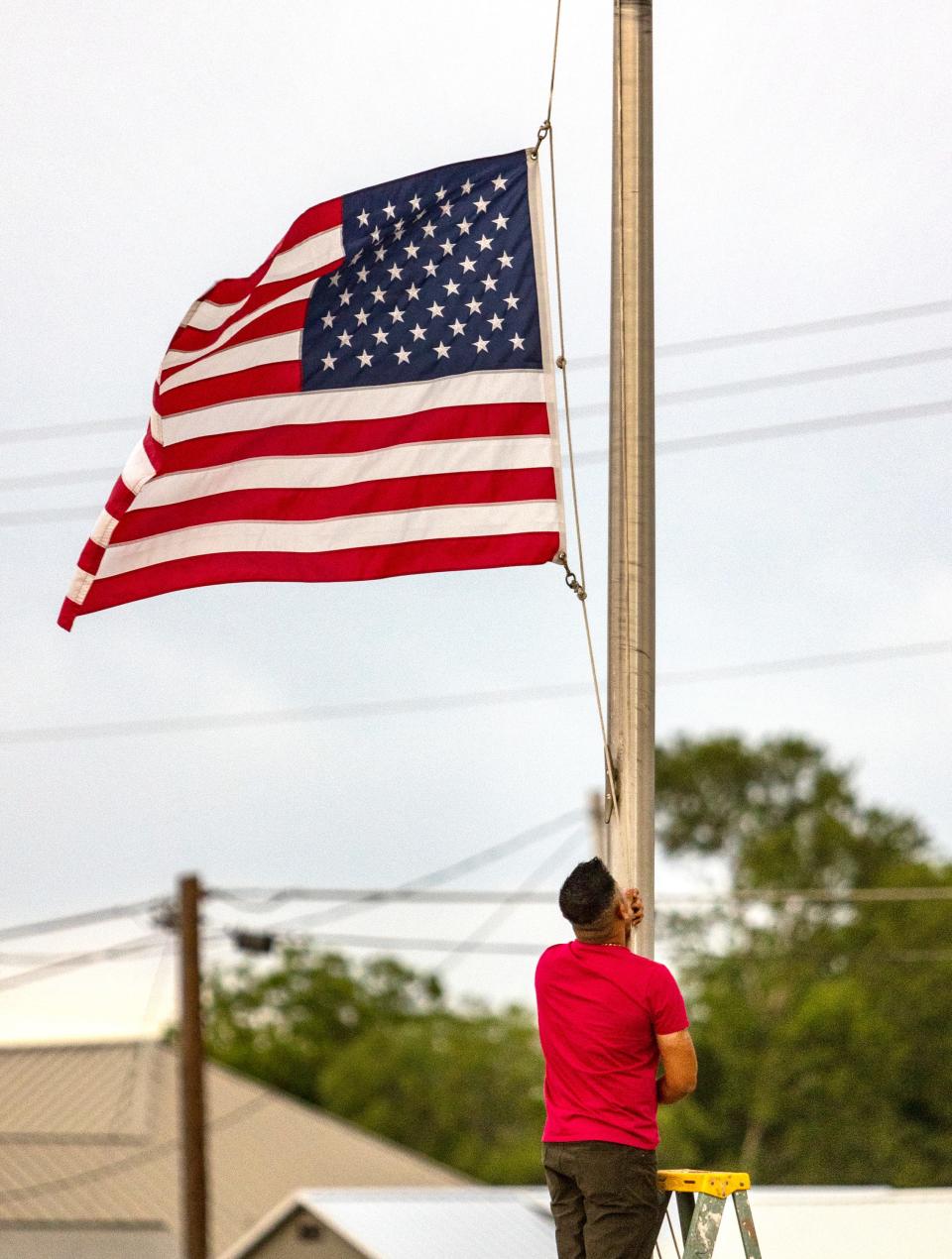 Janish Patel lowers the flag to half staff Tuesday, May 24, 2022, at his Uvalde, Texas, hotel hours after a gunman entered Robb Elementary School in Uvalde and killed multiple children and adults.