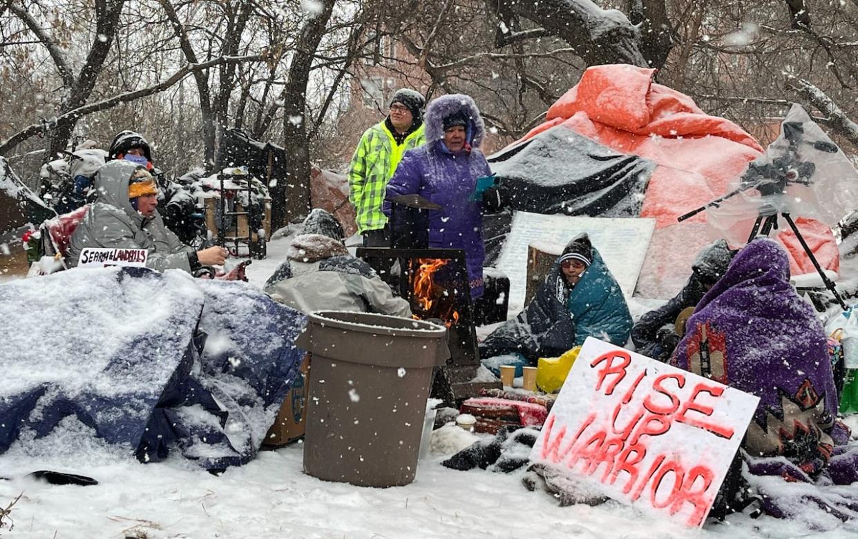 Police and city workers at an encampment in Edmonton in the area of 101A Avenue and 95th Street on Tuesday. The city is defending its approach to camp removals as a court battle over the policy continues. (Natasha Riebe/CBC - image credit)