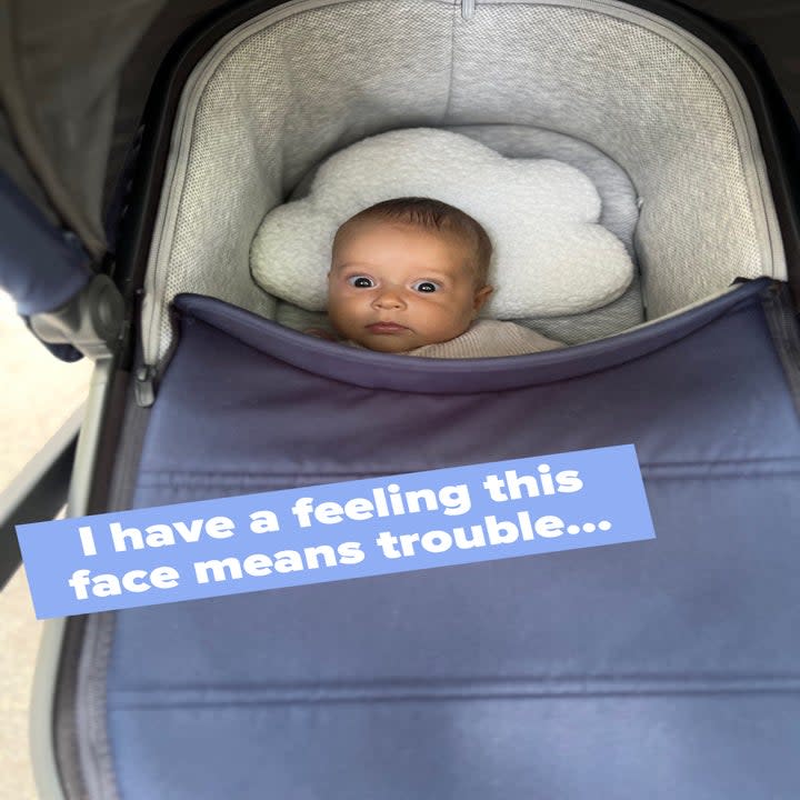 Ellie wide awake in her stroller with caption, 