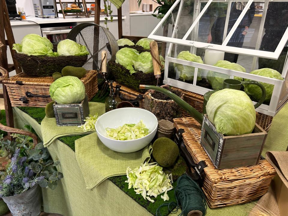 A table decorated with several heads of lettuce, as well as bowls containing shredded lettuce.