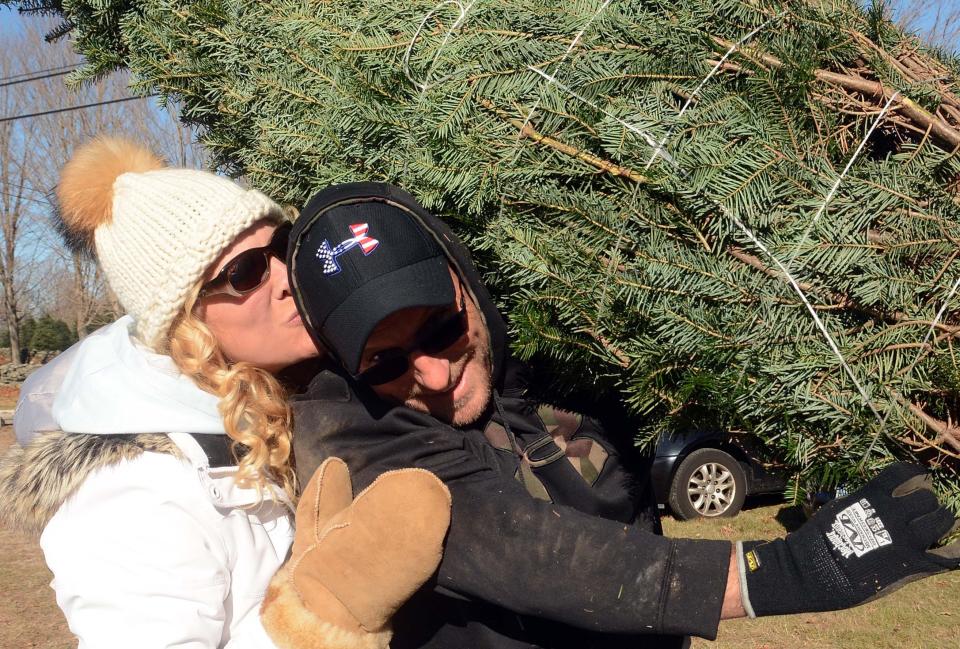 Tianne Pape of East Lyme gave her husband, Rick Pape, a kiss in 2018 as he carried the family Christmas tree to the car at Maple Lane Farms in Preston.