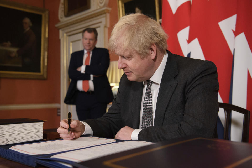 UK chief trade negotiator David Frost looks on as Britain's Prime Minister Boris Johnson signs the EU-UK Trade and Cooperation Agreement at 10 Downing Street, London Wednesday Dec. 30, 2020. The U.K. left the EU almost a year ago, but remained within the bloc’s economic embrace during a transition period that ends at midnight Brussels time —- 11 p.m. in London — on Thursday. European Commission President Ursula von der Leyen and European Council President Charles Michel signed the agreement during a brief ceremony in Brussels on Wednesday morning then the documents were flown by Royal Air Force plane to London for Johnson to add his signature. (Leon Neal/Pool via AP)