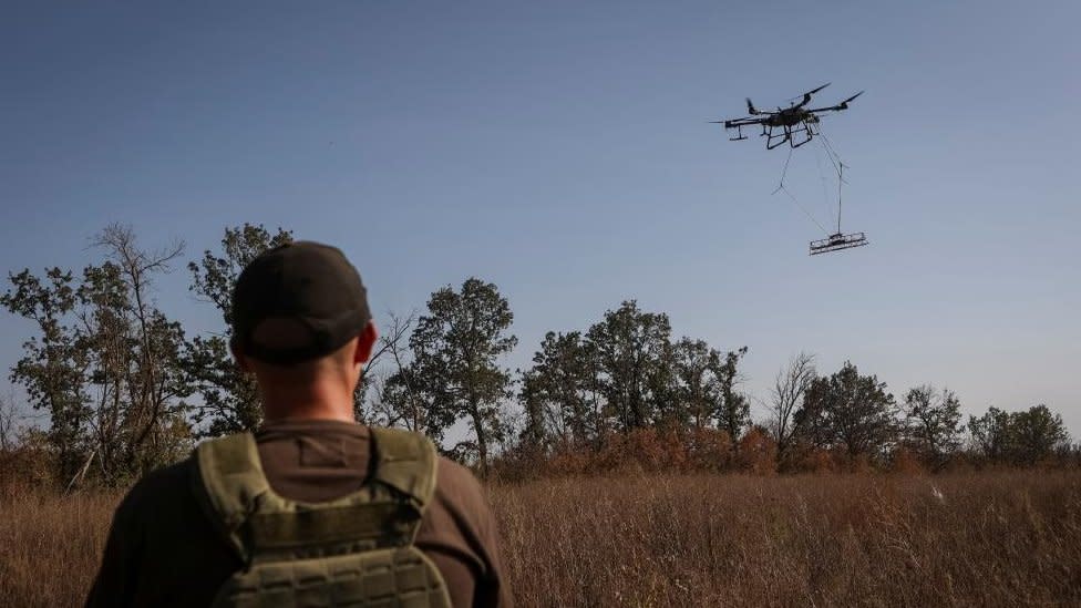 A member of the volunteer organization 'Postup' operates a drone with a metal detector for mine searching during demining a field, near the town of Derhachi, Kharkiv region