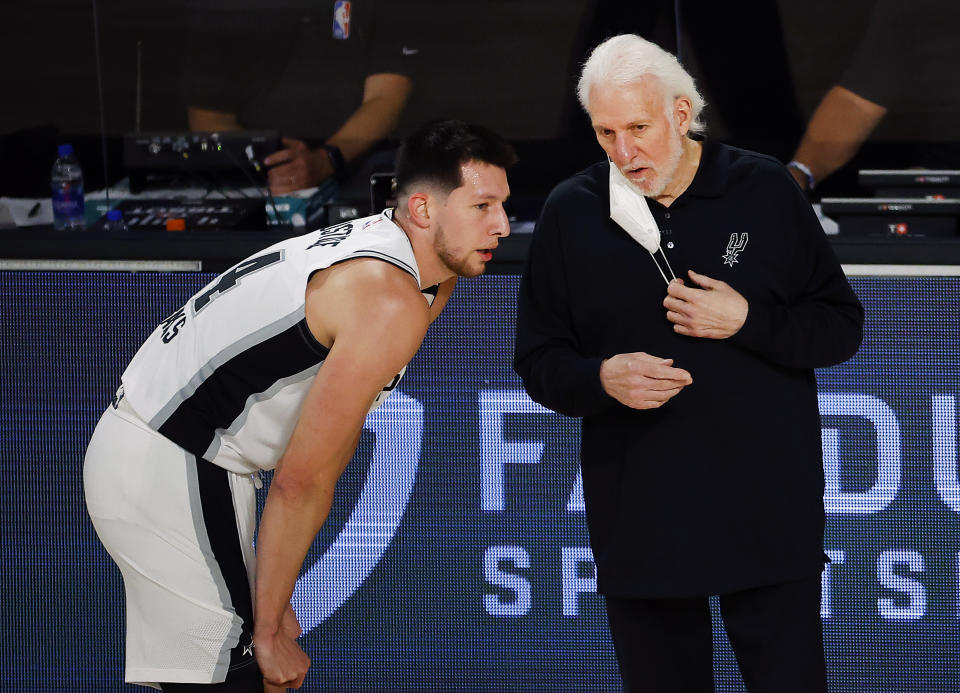 Gregg Popovich talks with Drew Eubanks on the sideline during a break in play.