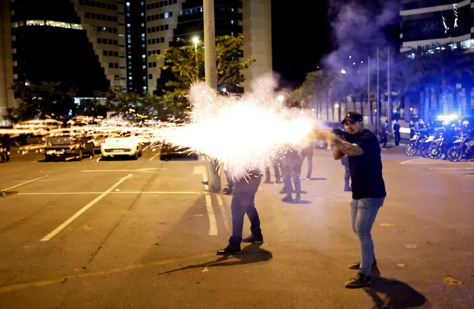 A police officer fires a shotgun as supporters of Brazilian President Jair Bolsonaro protest in Brasilia, Brazil, December 12, 2022. REUTERS/Ueslei Marcelino