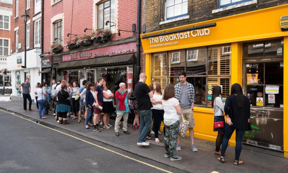 Customers queue outside the Breakfast Club cafe in Soho, London