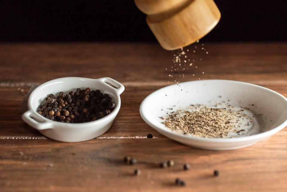 black pepper being ground into a small dish