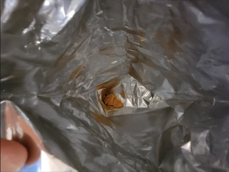 An empty snack bag with a small amount of leftover crumbs at the bottom
