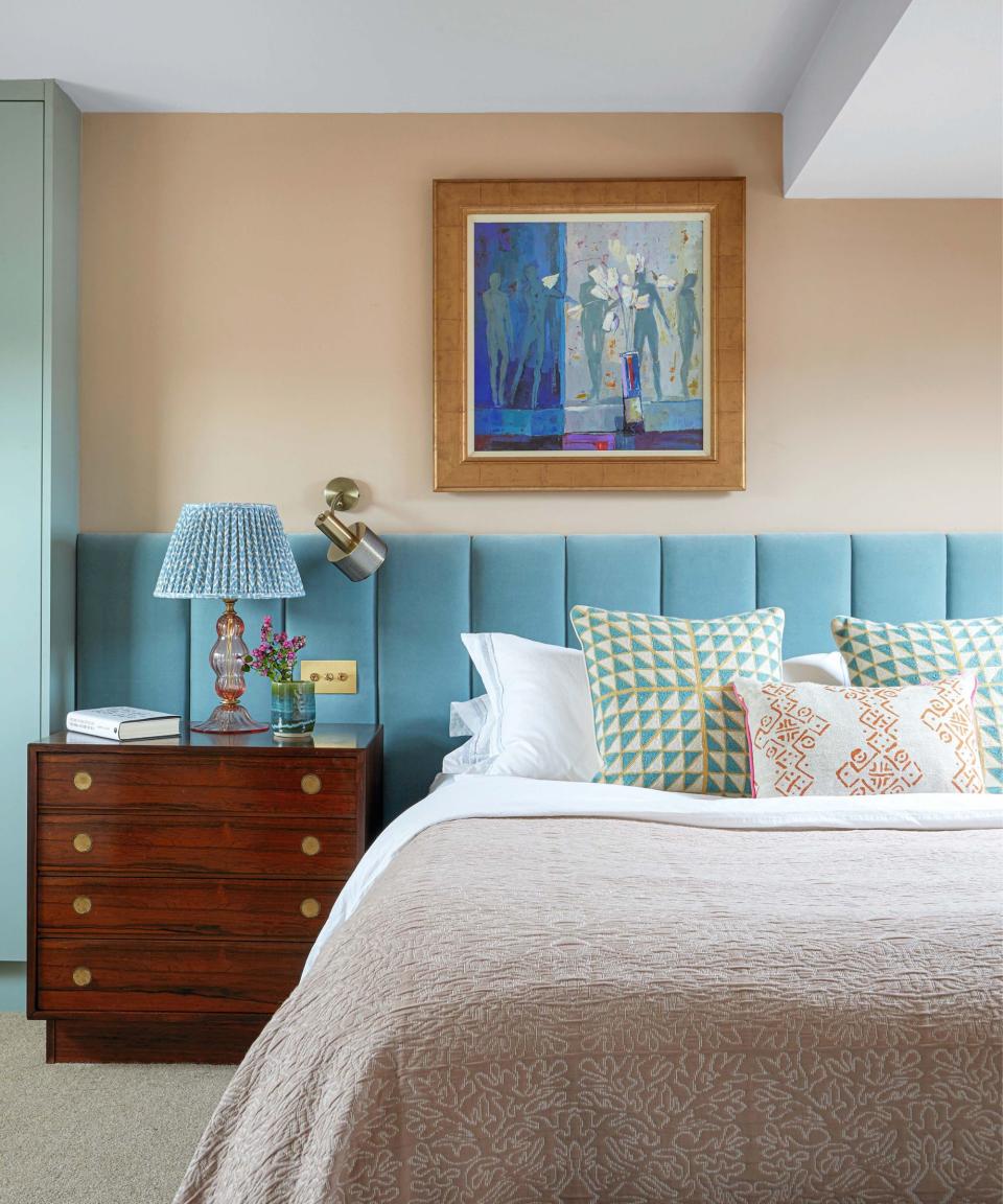 Blue and pale orange bedroom with velvet headboard