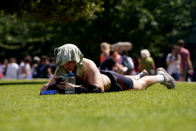 Man lies on his front in sun with T-shirt over his head for shade