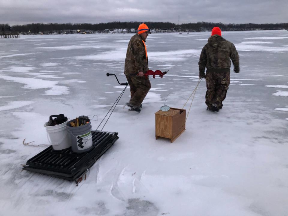 Cody Waldschmidt, left, with an auger in hand, and Christian Bryant, both of Dowagiac, head out onto Stone Lake in Cassopolis to ice fish Monday evening.