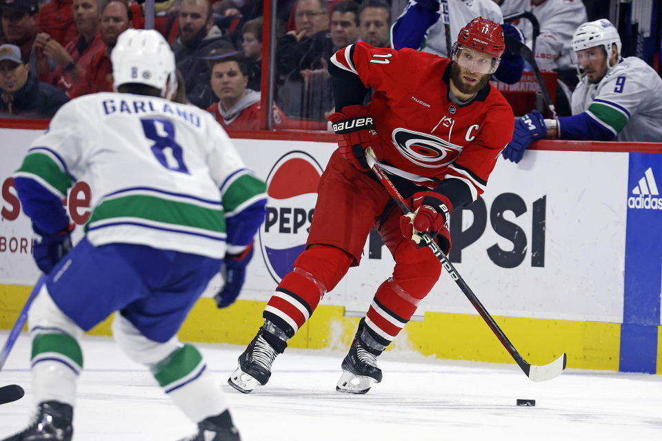 Carolina Hurricanes' Jordan Staal (11) moves the puck past Vancouver Canucks' Conor Garland (8) during the second period of an NHL hockey game in Raleigh, N.C., Tuesday, Feb. 6, 2024. (AP Photo/Karl B DeBlaker)