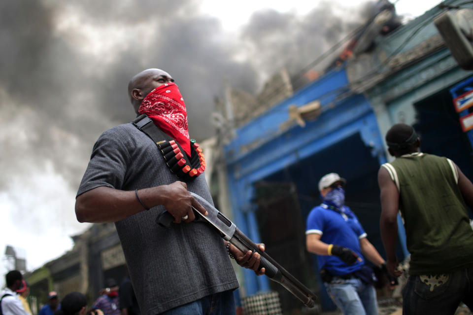 <p>A private security guard stands outside a burning store in downtown Port-au-Prince, Haiti, Jan.19, 2010. (Photo: Carlos Barria/Reuters) </p>