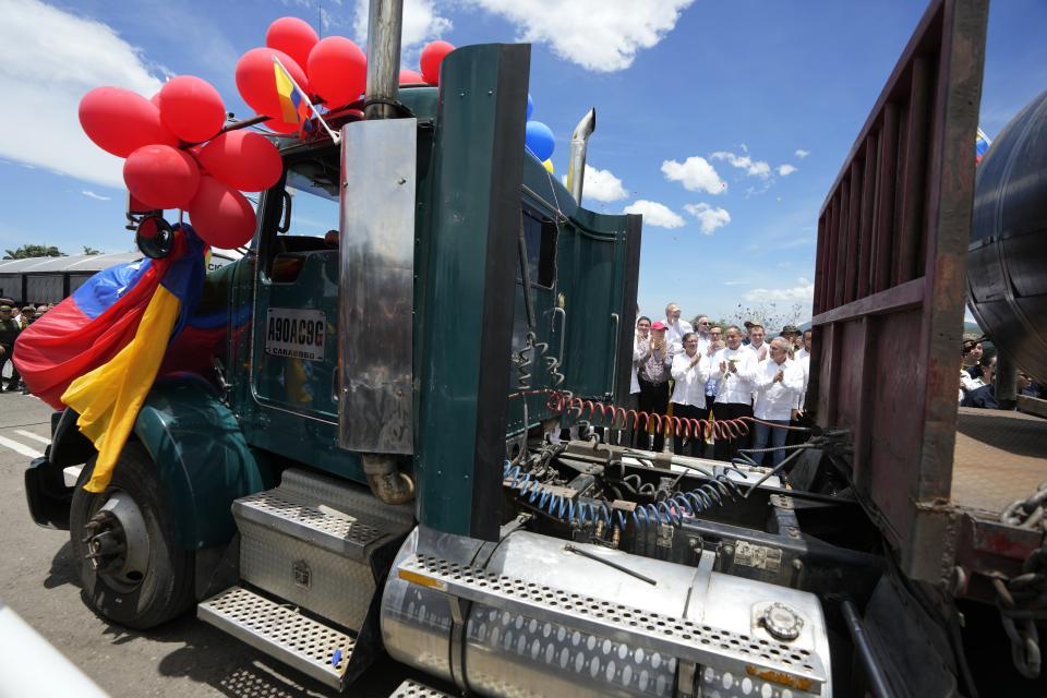 A Venezuelan cargo truck adorned with Venezuelan flags and balloons crosses the Simon Bolivar International Bridge during a ceremony to mark the bridge's reopening to cargo trucks between Cucuta, Colombia and San Antonio del Tachira, Venezuela, Monday, Sept. 26, 2022, in a ceremonial act to mark the resumption of commercial relations between the two nations. Behind in the crowd are Colombia's President Gustavo Petro and Venezuela's Transportation Minister Ramon Araguayan. (AP Photo/Fernando Vergara)