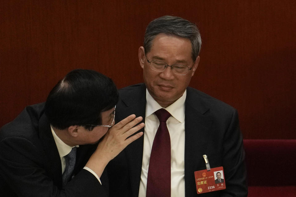 Politburo Standing Committee members Wang Huning, left, speaks near Li Qiang during a session of China's National People's Congress (NPC) at the Great Hall of the People in Beijing, Tuesday, March 7, 2023. The pro-business track record of the man poised to become China's top economic official on Saturday will make Li Qiang's term a test of whether he might moderate President Xi Jinping's tendency to intervene. (AP Photo/Ng Han Guan)