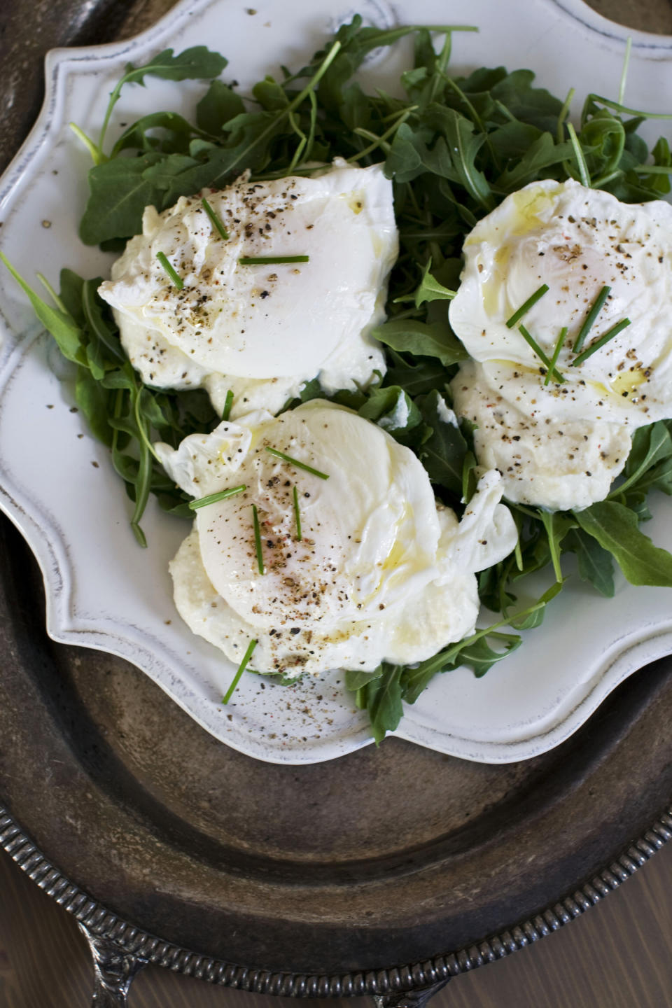 In this image taken Dec. 3, 2012, poached eggs over ricotta cheese on arugula are shown served on a plate in Concord, N.H. (AP Photo/Matthew Mead)