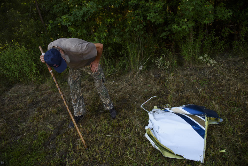 Dan Plas looks at a piece of debris from a small plane that crashed into a home in Hope Mills, N.C., late Thursday evening on Friday, June 28, 2019. A single-engine plane crashed into the home, killing the pilot and someone inside the house, authorities said. Another person in the house was seriously hurt. (Melissa Sue Gerrits /The Fayetteville Observer via AP)