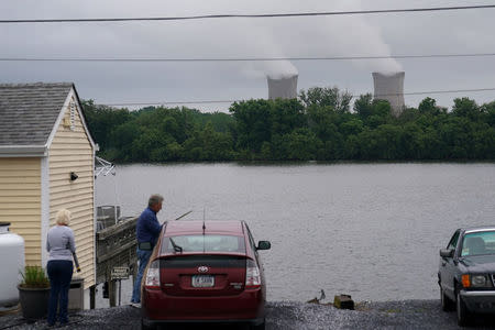 People work on a car across the Susquehanna River in front of the Three Mile Island nuclear power plant in Goldsboro, Pennsylvania, U.S. May 30, 2017. REUTERS/Carlo Allegri