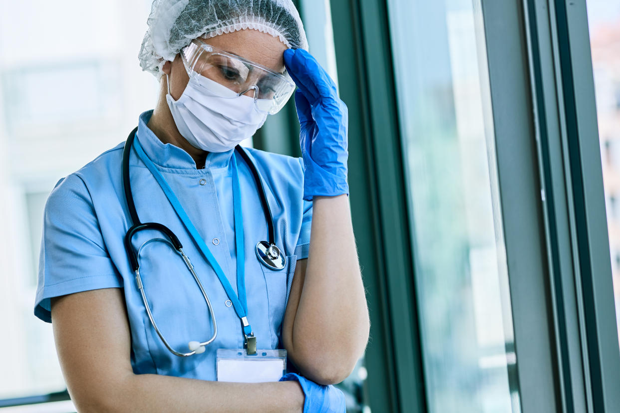 Worried nurse having a headache while working at the hospital during corona virus pandemic.