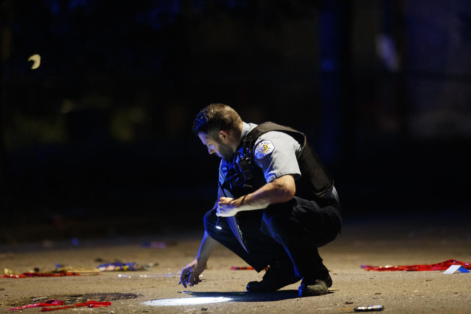 An officer investigates the scene of a shooting in Chicago on Sunday, July 5, 2020. At least a dozen people, including a 7-year-old girl at a family party and a teenage boy, were killed in Chicago over the Fourth of July weekend, police said. Scores of people were shot and wounded. (Armando L. Sanchez/Chicago Tribune via AP)