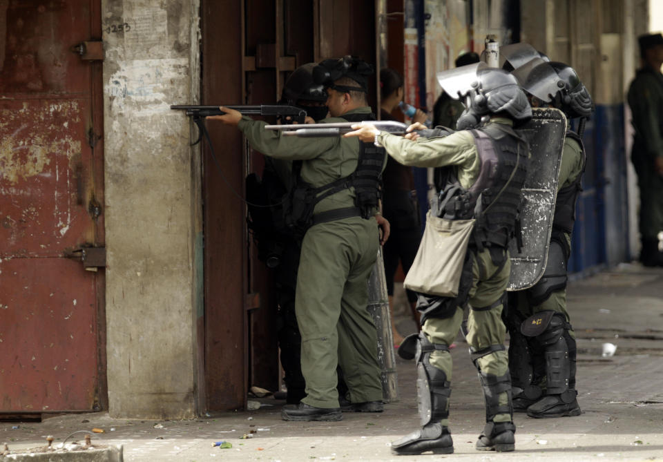 Riot police officers aim their weapons toward demonstrators during a protest in downtown Colon, Panama, Tuesday, Oct. 23, 2012. Demonstrators protested over a new law allowing the sale of state-owned land in the duty-free zone next to the Panama Canal. Protesters said the land is already being rented and it makes no sense to sell it. They said the government should instead raise the rent and invest the money in Colon, a poor and violent city. (AP Photo/Arnulfo Franco)