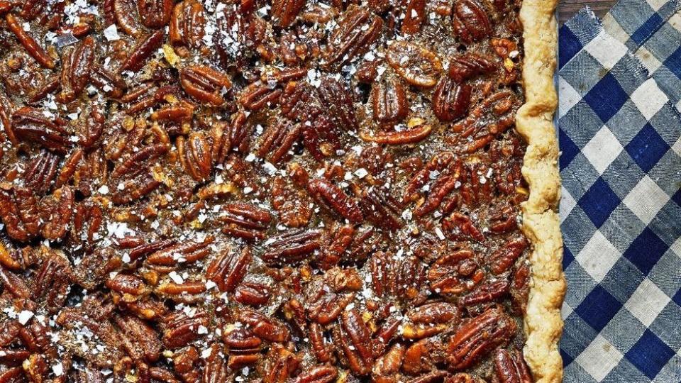 nancy fullers pecan slab pie in a rectangle pan on a navy blue gingham kitchen towel